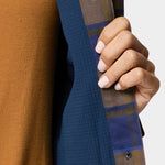 A person with light pink manicured nails holds open a Duck Camp W's Campfire Shacket in Pintail Plaid, revealing a brown top underneath.