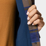 A person with light pink manicured nails holds open a Duck Camp W's Campfire Shacket in Pintail Plaid, revealing a brown top underneath.