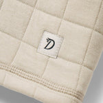 A close-up of the W's Cheyenne Quilted Crew by Duck Camp, a beige cotton crewneck sweater with quilted texture, stitched border, and a small white tag with the "D" logo—perfect for comfortable layering.