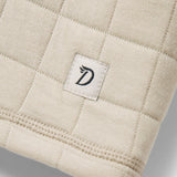 A close-up of the W's Cheyenne Quilted Crew by Duck Camp, a beige cotton crewneck sweater with quilted texture, stitched border, and a small white tag with the "D" logo—perfect for comfortable layering.