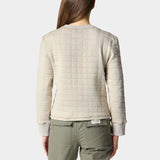 A person with long brown hair faces away, wearing the Duck Camp W's Cheyenne Quilted Crew and olive green pants—this quilted cotton crew neck sweater from Duck Camp is a comfy mid-layer ideal for everyday layering.