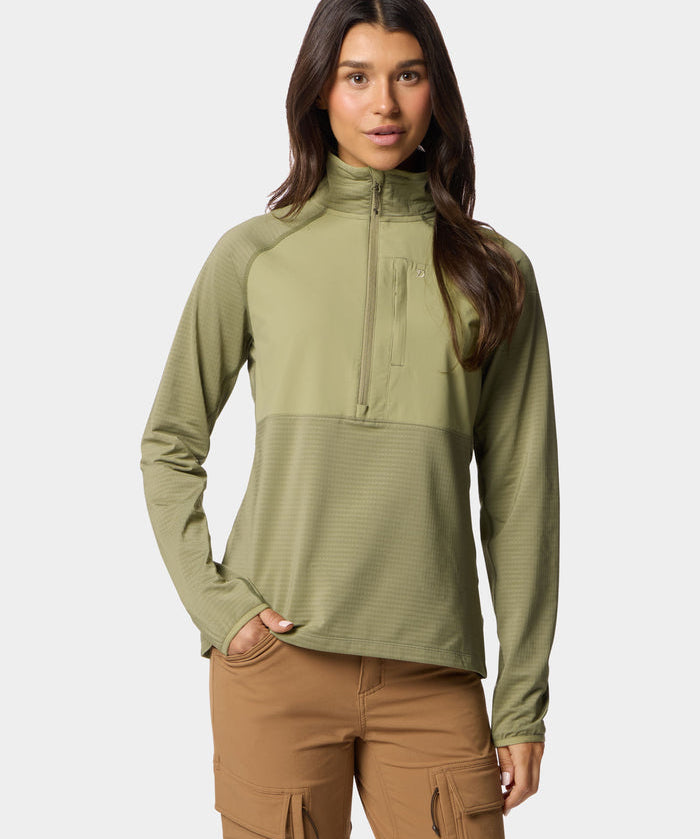 A woman stands facing forward, wearing the Duck Camp W's Lightweight Grid Tech Fleece Half Zip in Sagebrush and tan cargo pants, with one hand in her pocket against a plain background.