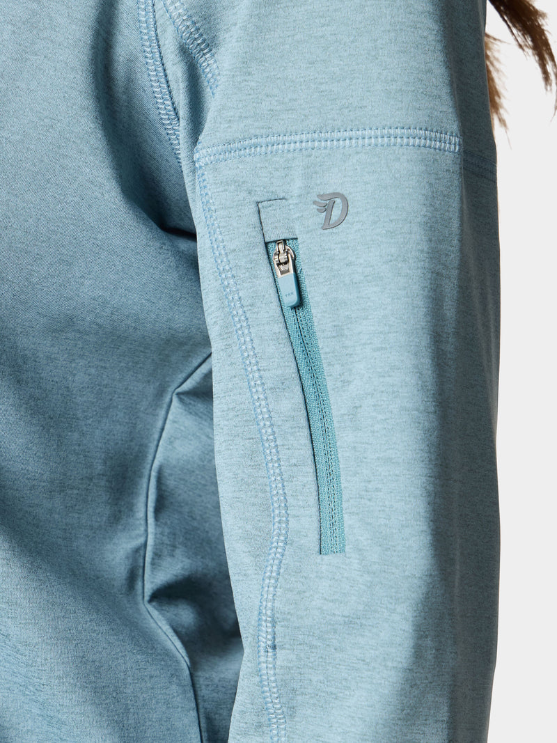 Close-up of the Duck Camp W's Rockport Hoodie in Heathered Trooper, showing a light blue sleeve with a small vertical zippered pocket and visible stitching, made from cooling material for comfort.