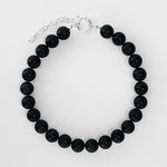 The Yona Collar by Kara Yoo features large, round black beads with a silver adjustable chain clasp, inspired by handmade Vancouver jewelry, and is displayed on a white background.