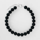 The Yona Collar by Kara Yoo features round black beads and a silver adjustable chain with clasp, crafted in Vancouver, shown arranged in a circle on a white background.