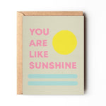 The "You Are My Sunshine" card by Daydream Prints features pink text, a yellow sun, and two blue lines on A2 size. Comes with a recycled envelope. Designed in Portland, Oregon.