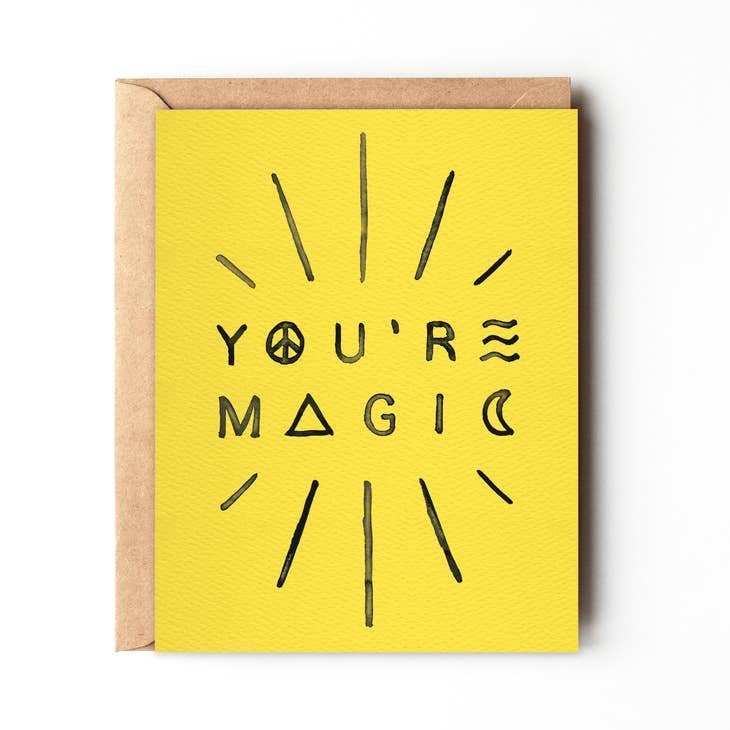 A yellow "YOU'RE MAGIC" greeting card with black text and radiating lines from Daydream Prints, paired with a recycled envelope. Made in Portland.