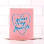 The "You're My Favorite" greeting card by Daydream Prints features blue handwritten text inside a blue heart on a pink card, paired with a recycled envelope. Made in Portland.