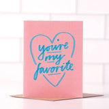 The "You're My Favorite" greeting card by Daydream Prints features blue handwritten text inside a blue heart on a pink card, paired with a recycled envelope. Made in Portland.