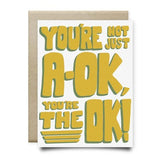 The You're Not Just A-OK Card by Anvil Cards features bold yellow and green text on linen paper, is A2 size, blank inside, and includes a brown envelope.