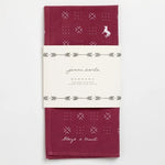 The Jenni Earle "Blaze A Trail" bandana is hand-dyed maroon with white geometric patterns, a small fox illustration, and the phrase "Blaze a Trail," wrapped in a branded paper label.
