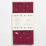 Folded maroon cotton bandana by Jenni Earle with white geometric and animal prints, hand-dyed look, and wrapped in a “Blaze A Trail” label with decorative arrows.