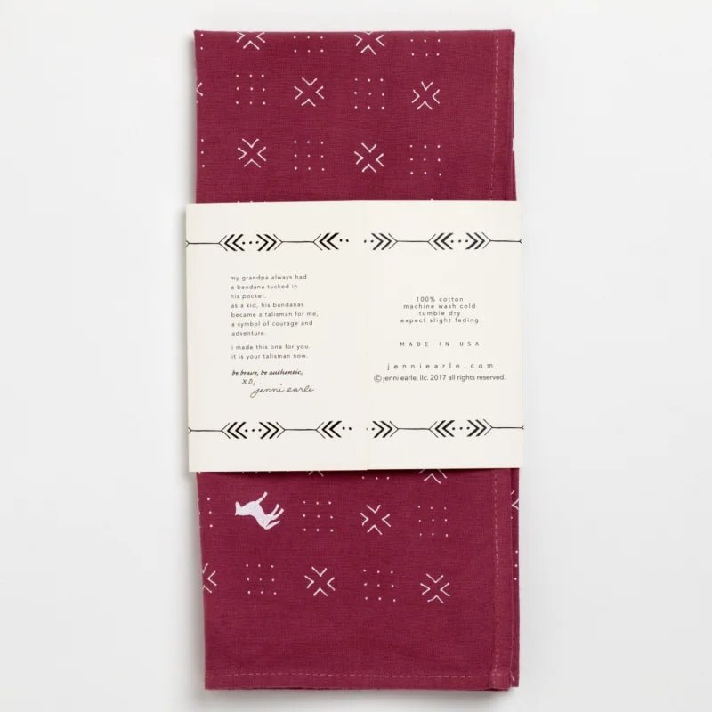 Folded maroon cotton bandana by Jenni Earle with white geometric and animal prints, hand-dyed look, and wrapped in a “Blaze A Trail” label with decorative arrows.