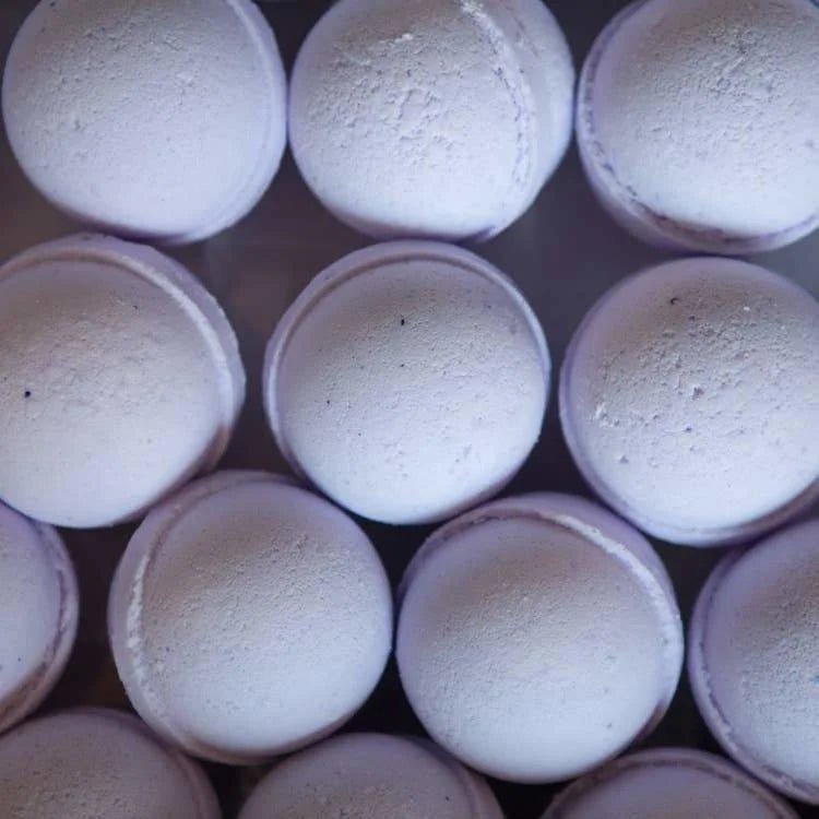 Rows of round, light purple Bath Bomb | French Lavender by Old Whaling Co., infused with epsom salt, are arranged in a grid pattern and viewed from above.