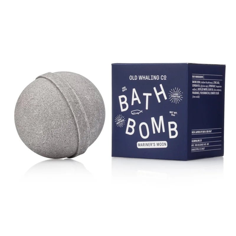 A gray bath bomb with Epsom salts sits next to a blue box labeled "Bath Bomb | Mariner's Moon | Old Whaling Co." by Old Whaling Co.