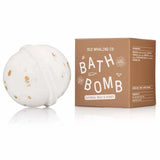 A white bath bomb with oat pieces sits next to a brown box labeled "Bath Bomb | Oatmeal Milk + Honey | Old Whaling Co."—ideal for a soothing soak.