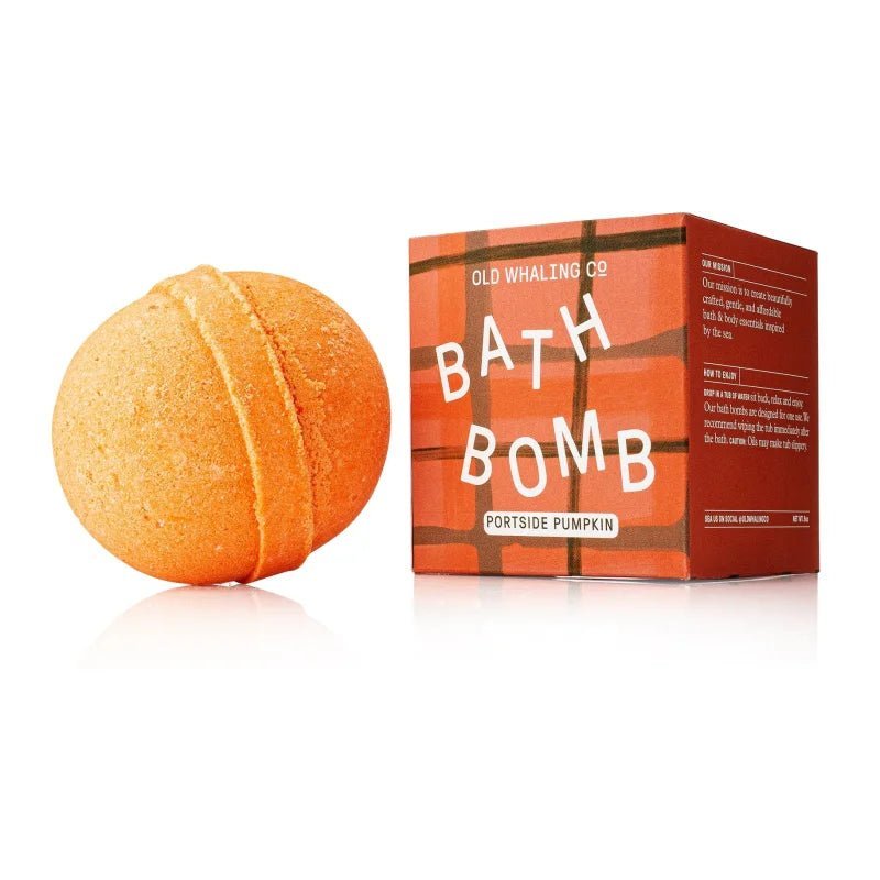 An orange Bath Bomb | Portside Pumpkin from Old Whaling Co. rests by its packaging, labeled "Old Whaling Co. Bath Bomb Portside Pumpkin," set against a plaid backdrop.