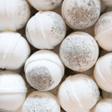 A cluster of Old Whaling Co. Bath Bombs in Seaweed & Sea Salt, white and spherical with gray sea clay speckles, is shown.