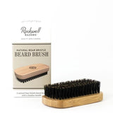 The Beard Brush | Rockwell Razors, featuring natural boar bristles and a bamboo handle, is displayed beside its branded box.
