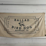 The Bird Dog Flag | Large by Ballad of the Bird Dog features a beige, neon-style design with black "Ballad of the Bird Dog, Brenham, TX, Estd 2018" text and a central dog illustration.