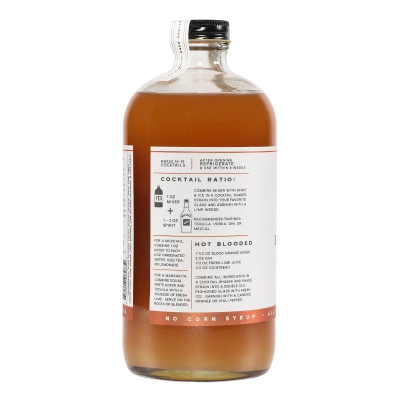 A glass bottle of Yes Cocktail Co.'s Blood Orange & Chili Pepper Cocktail Mixer, with an amber liquid and a white label listing ingredients and cocktail mixing instructions—highlighting flavors of sweet citrus and smoked pepper.
