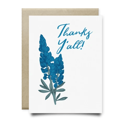 The Bluebonnets Thanks Yall Card by Anvil Cards features blue flowers and “Thanks Y’all!” on the front, printed on linen paper, includes a plain brown envelope, and is blank inside for your message.