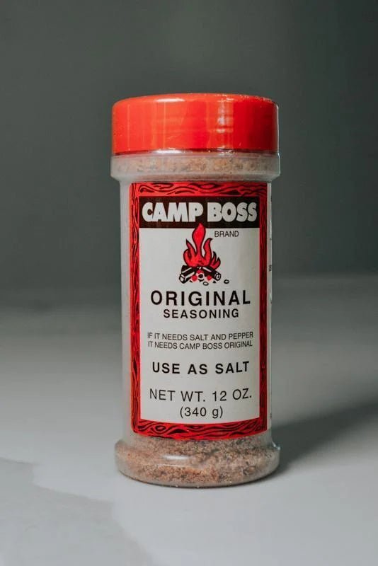A 12 oz Camp Boss Seasoning container with a red lid includes label instructions to use this bold Texas blend as salt.