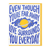 The "Love Surrounds You" card by Lucky Horse Press features Saturn and stars, is letterpress printed in the USA, and says “Even though you’re far away, love surrounds you everyday” in bold blue lettering.