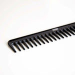 The Uppercut Deluxe CB11 Rake Comb by Uppercut Deluxe, featuring wide teeth and a black finish, is displayed at an angle on a white surface.