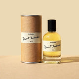 A bottle of Desert Lavender by Saguara Perfumes rests beside its cylindrical cardboard box against a beige background.