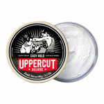 An open tin of Easy Hold by Uppercut Deluxe reveals the white, light hold, matte finish hair cream inside, with a lid featuring vintage-style boxing artwork.