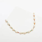 The Edith Necklace by Larissa Loden features white oval freshwater pearls, multicolored African Christmas beads, and gold fill beads arranged delicately on a white background.