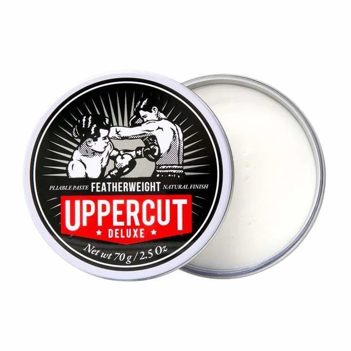 A round tin of Uppercut Deluxe Featherweight Paste with a partially open lid shows the white product inside. The lid displays an illustration of two boxers and the Uppercut Deluxe branding.