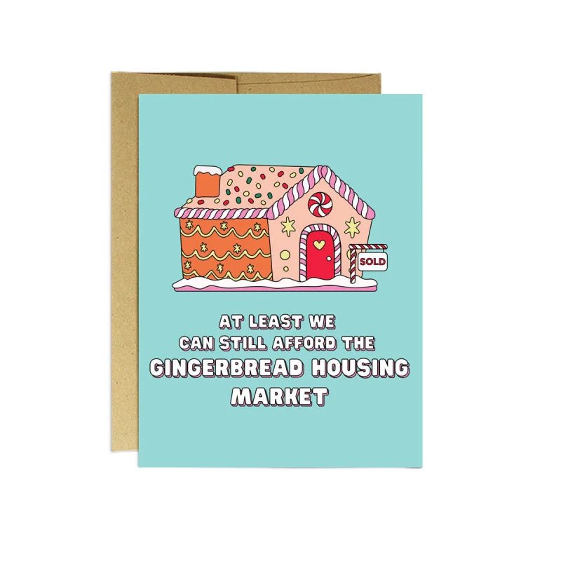 Party Mountain Paper co.'s "Gingerbread Housing Market" Christmas Card features a cartoon gingerbread house with a "SOLD" sign and the phrase: "At least we can still afford the gingerbread housing market." Blank inside, made in Canada.
