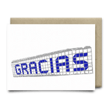 The Gracias Blue Tiles Card by Anvil Cards features "GRACIAS" in blue mosaic tile design on linen paper, blank inside for your message. Includes a brown envelope. A2 size.