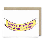 The Happy Birthday Banner Card by Anvil Cards is an A2 linen card with a yellow banner and purple "HAPPY BIRTHDAY" text, blank inside, and comes with a brown envelope on a white background.