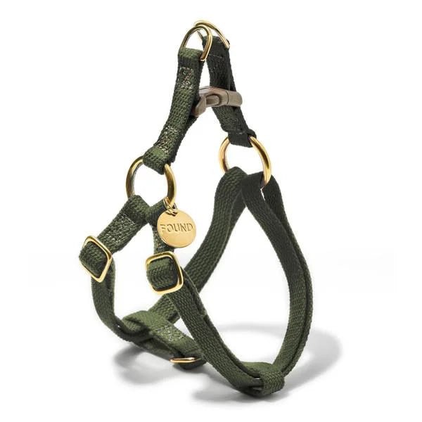 The Found My Animal Harness is a green fabric dog harness with gold metal rings, adjustable straps, a plastic clasp, and a round gold tag engraved "FOUND." Handmade for comfort and security.