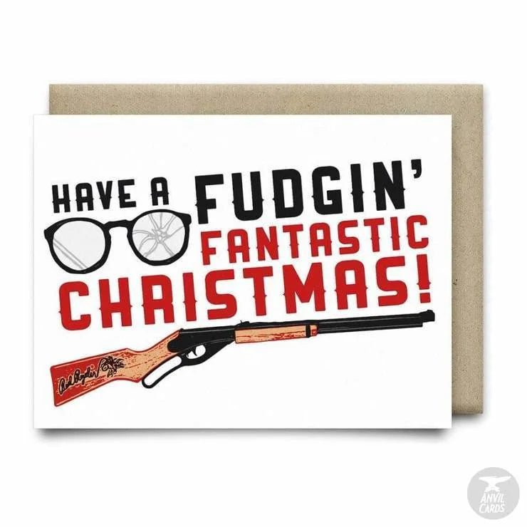 The "Have a Fudgin' Fantastic Christmas Card" by Anvil Cards features glasses, a BB gun illustration, and bold black and red text on linen paper. A2 size; blank inside for your message.