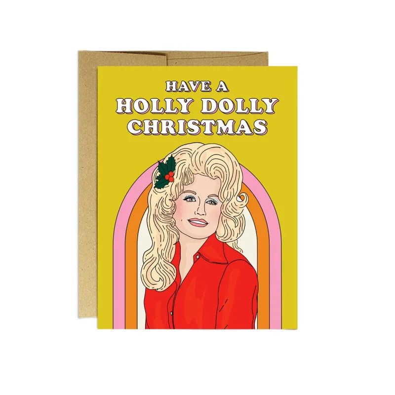 Holly Dolly Christmas card by Party Mountain Paper co. features an illustrated blonde woman in a red shirt with holly in her hair and "Have a Holly Dolly Christmas" on yellow. A2 size, blank inside, printed in Toronto.