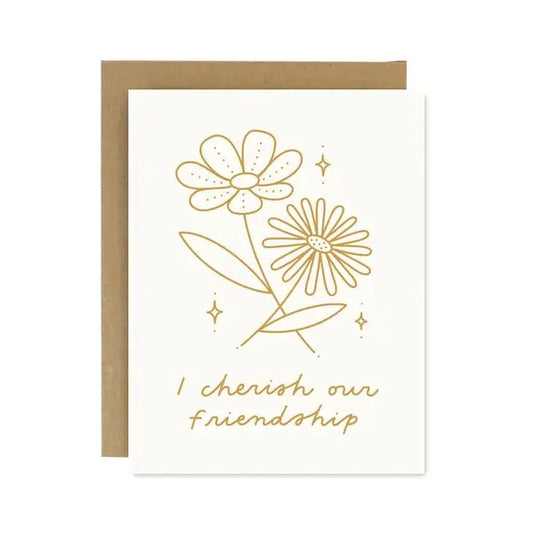 The I Cherish Our Friendship Card by Worthwhile Paper features two gold line-drawn flowers and "I cherish our friendship" on the front, paired with a recycled brown envelope.