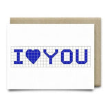 The I Heart You Card by Anvil Cards is a white A2 linen paper greeting card with a blue “I ♥ YOU” grid design, blank inside for your message, and comes with a brown envelope.