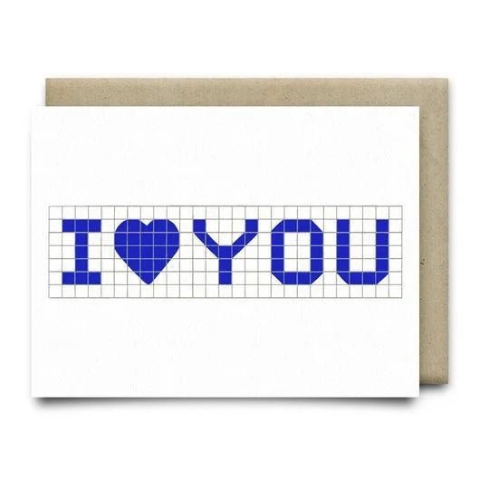 The I Heart You Card by Anvil Cards is a white A2 linen paper greeting card with a blue “I ♥ YOU” grid design, blank inside for your message, and comes with a brown envelope.