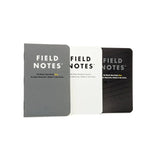 Three Field Notes "Ignition" notebooks by Field Notes, in gray, white, and black covers, are side by side on a white background. Each shows its type and page details—ideal for bullet journaling or checklist use.