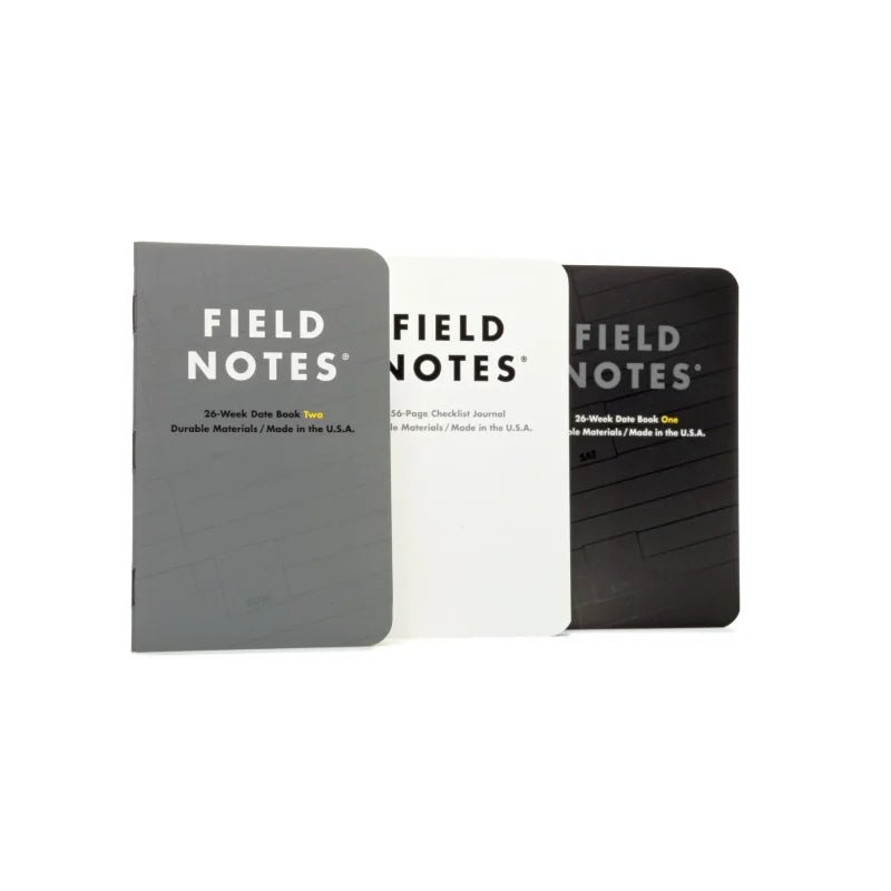 Three Field Notes "Ignition" notebooks by Field Notes, in gray, white, and black covers, are side by side on a white background. Each shows its type and page details—ideal for bullet journaling or checklist use.