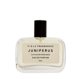 A clear glass bottle of Juniperus | Fiele Fragrances by Fiele Fragrance, a natural eau de parfum with a black cap and cream label, 50 mL.