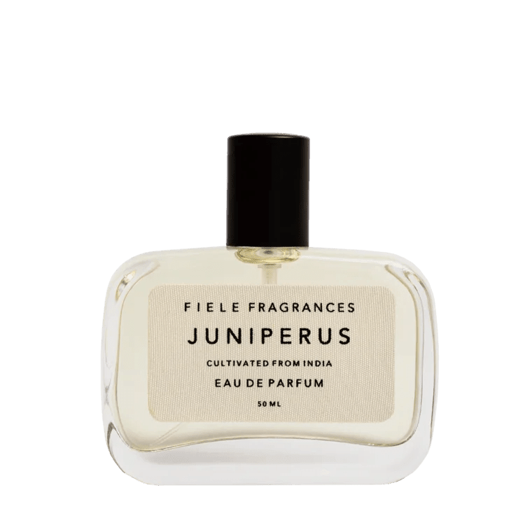A clear glass bottle of Juniperus | Fiele Fragrances by Fiele Fragrance, a natural eau de parfum with a black cap and cream label, 50 mL.
