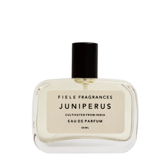A clear glass bottle of Juniperus | Fiele Fragrances eau de parfum by Fiele Fragrance, featuring a black cap and beige label with product details.