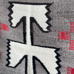 Close-up of the Vintage Klagetoh Rug Circa 1950, showcasing a geometric black and white arrow pattern with red accents on gray, inspired by classic Navajo weaving.