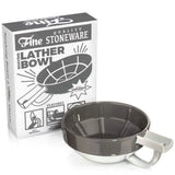 A gray and white Fine Accoutrements Lather Bowl with handle is displayed before its box labeled "Fine Quality Stoneware Shaving Lather Bowl," ideal for use with your favorite shaving brush and traditional shaving soap.
