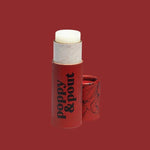 A Poppy & Pout Lip Balm in a red tube, cap off to reveal the balm stick, is displayed against a matching red background.